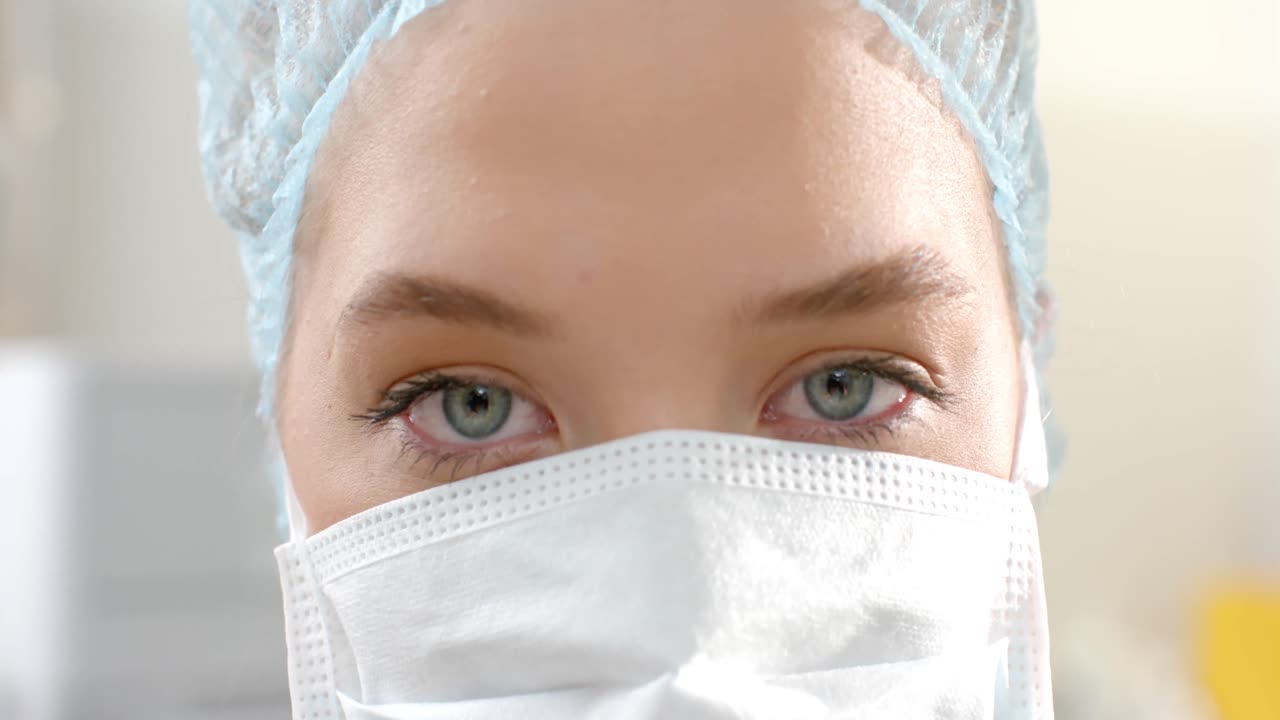 retrato de una cirujana caucásica con gorra quirúrgica y máscara facial, cámara lenta