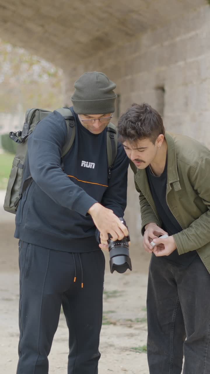 Dos hombres revisando fotos en una cámara al aire libre