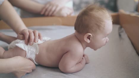 newborn-boy-with-fair-hair-lies-on-table-and-enjoys-massage