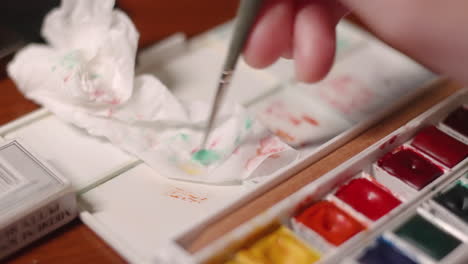 hand wiping the paint brush into white tissue