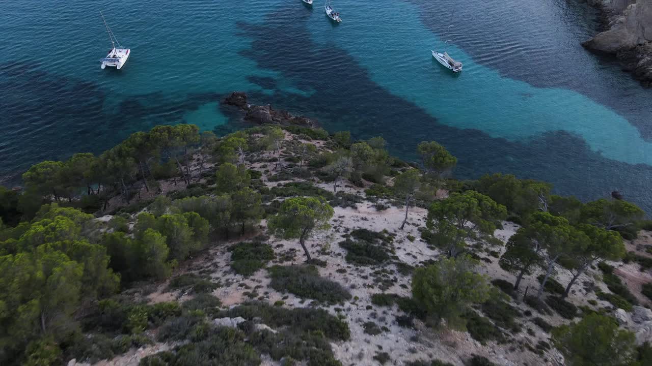Droneudsigt over skrånende klipper og fortøjede sejlbåde ved Cala d'egos Strand