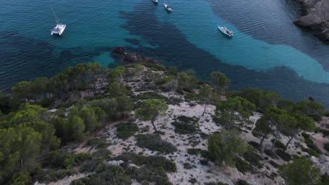 Drohnenansicht-Der-Absteigenden-Klippen-Und-Blick-Auf-Segelboote,-Die-Am-Strand-Von-Cala-D&#39;Egos-Angedockt-Sind