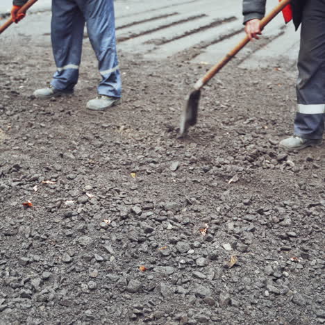 workers in uniform with shovels during road street repairing works. street resurfacing. fresh asphalt construction. close-up