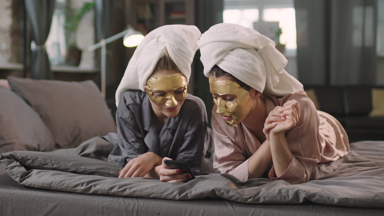 Girls In Sheet Masks Looking At Smartphone