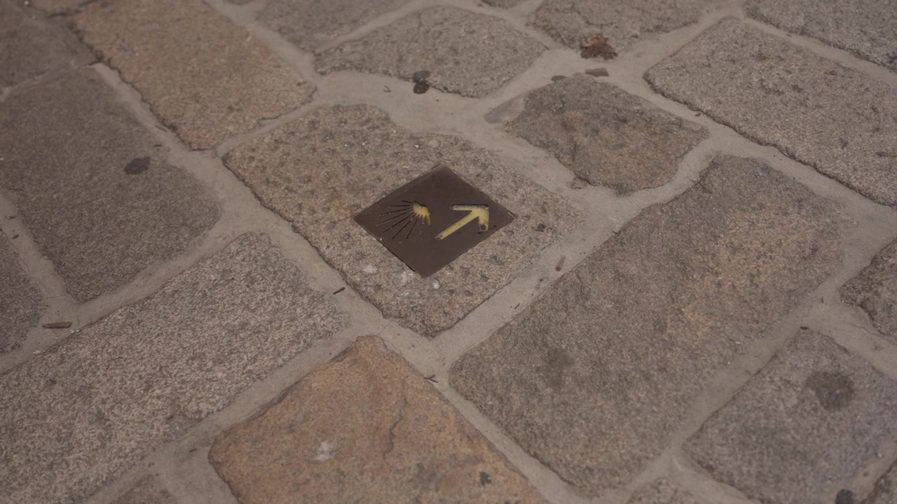 Camino de Santiago plaque with scallop shell and yellow arrow set in granite paving