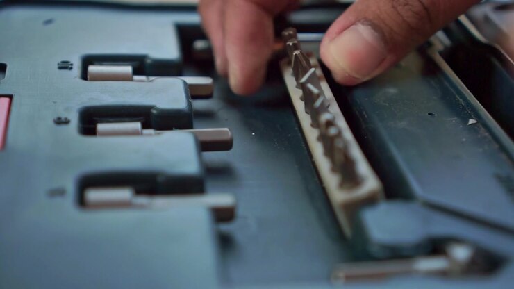 Person picking up screwdriver bit from organized toolbox, close up view, workshop hardware organization footage scene.