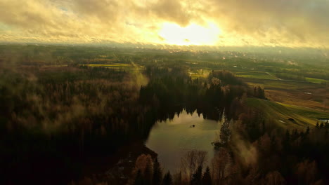 Espectacular-Vista-Aérea-Del-Paisaje-Hacia-El-Sol-En-La-Hora-Dorada-Con-Nubes-En-Movimiento