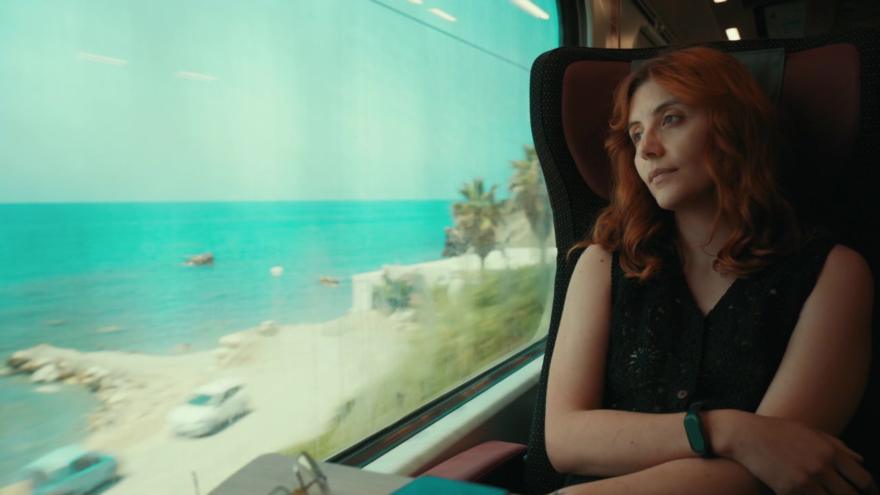 Uma mulher olha pela janela de um trem de férias de verão para o mar e a praia