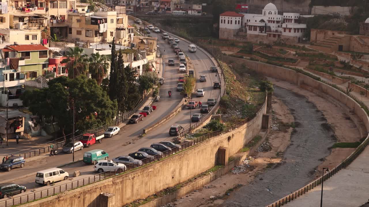 coches conduciendo por la carretera cortando a través de un valle del río hacia las montañas en trípoli, norte del líbano