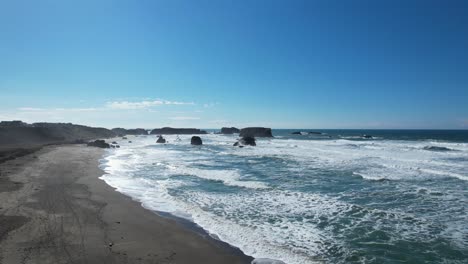 Beautiful-4K-aerial-drone-shot-with-blue-skies-gliding-over-Bandon-beach-in-Oregon-on-a-sunny-day