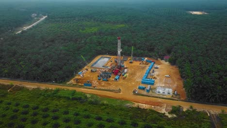 cinematic drone shot of onshore drilling and workover rig structure and rig equipment for oil exploration and exploitation in the middle of jungle surrounded by palm oil trees during sunset time