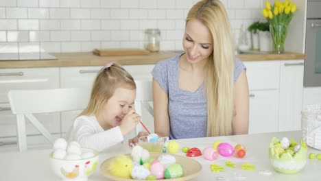 young female and little girl painting eggs