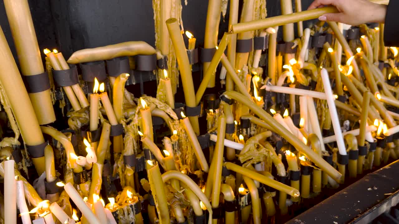 Primo piano di una donna che accende candele come voto al Santuario di Fatima, Portogallo.