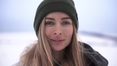 mujer sonriente parada mira la cámara en el valle nevado de invierno