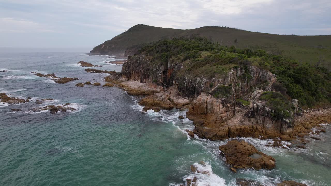 Waves Splashing On Rugged Shore Of Diamond Head In Barrington Coast, New South Wales, Australia. aerial approaching shot