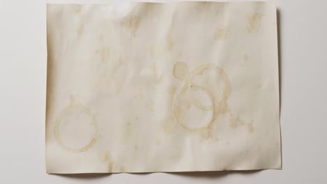 video of close up of piece of paper with round glass coffee marks on white background