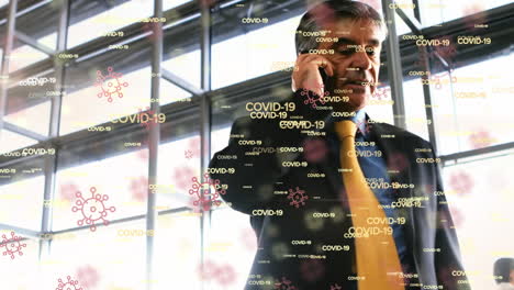 animación de palabras e iconos flotantes de covid-19 sobre un hombre biracial hablando por teléfono