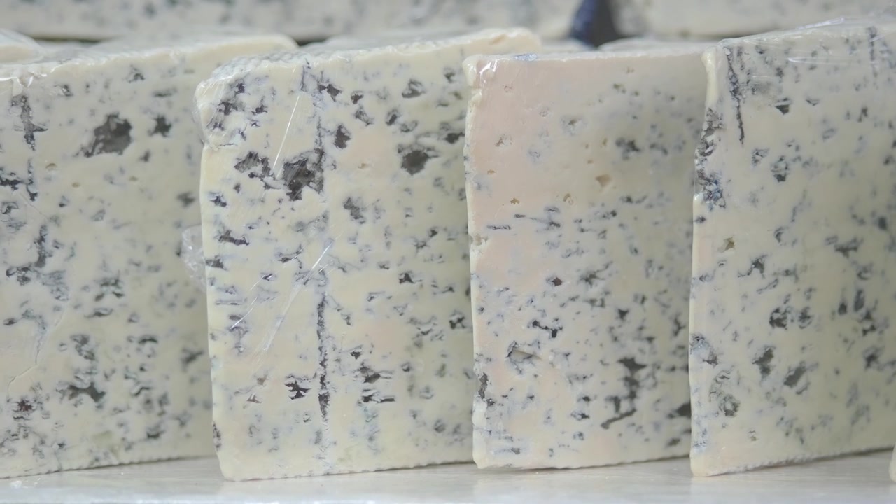 Fette di formaggio erborinato disposte su uno scaffale espositivo