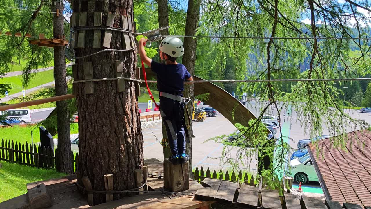Children crossing a forest via ferrata in slow motion in Alta Badia, Dolomites, Italy during a family outdoor adventure practicing clipping in