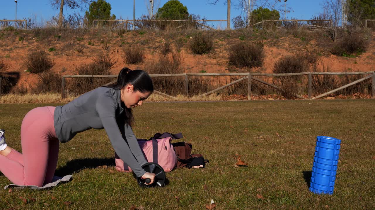 mujer haciendo ejercicio con una rueda abdominal en un parque. ejercicio al aire libre