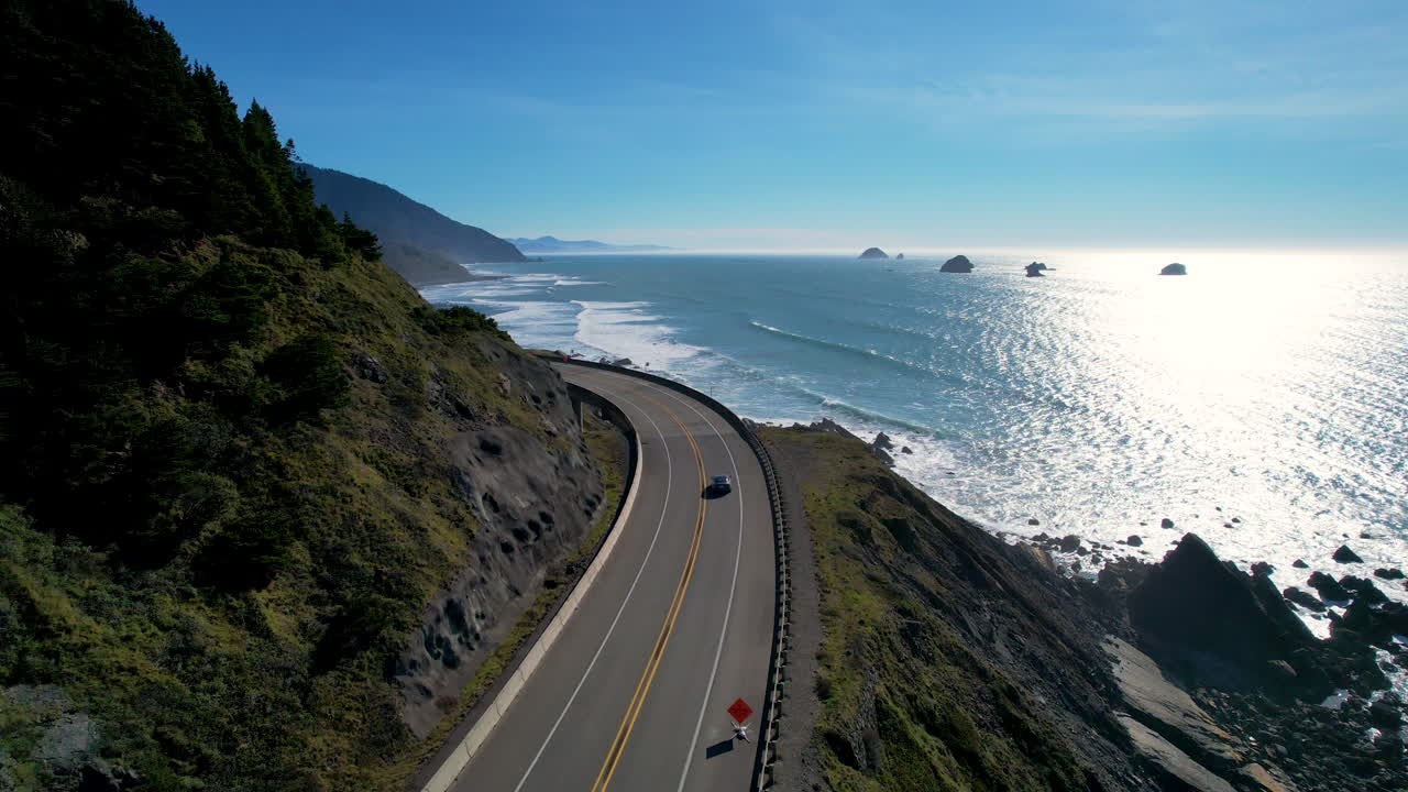 A car driving along the Oregon Coast Highway with the ocean in the background.