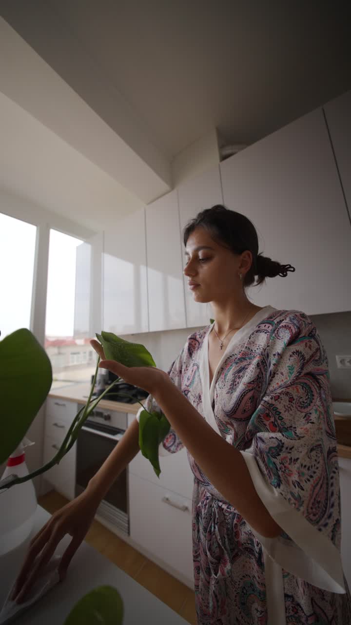 Woman Cleaning a Houseplant in the Kitchen