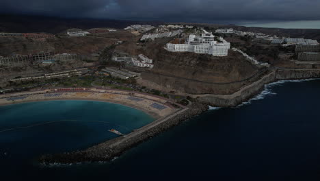 Fantástica-Toma-Aérea-En-órbita-De-La-Playa-De-Amadores-Y-Los-Grandes-Hoteles-De-La-Zona,-Durante-La-Puesta-De-Sol-En-La-Isla-De-Gran-Canaria