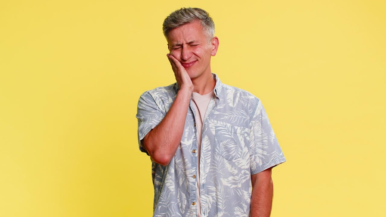 Adult man touching cheek with painful expression suffering from strong toothache dental discomfort