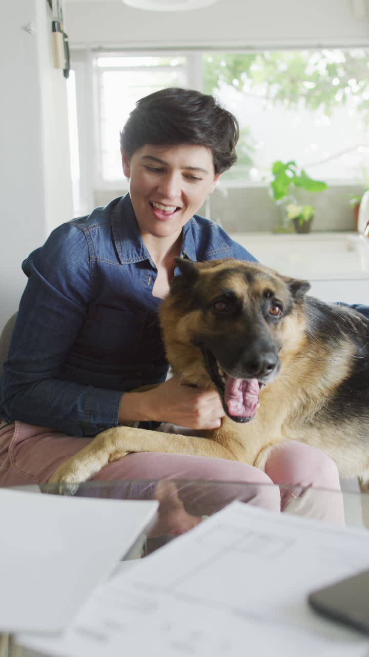 video vertical de una mujer caucásica feliz acariciando a su perro en casa