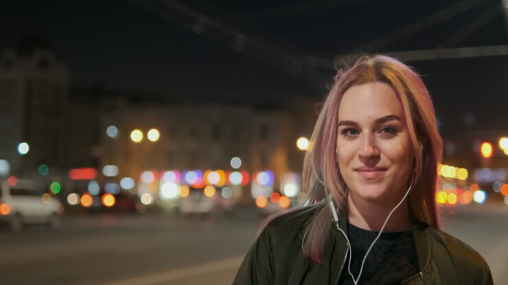 Giovane donna sorridente che indossa le cuffie e ascolta musica.