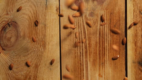 overhead shot of almond nuts dropping onto wooden surface shot in slow motion