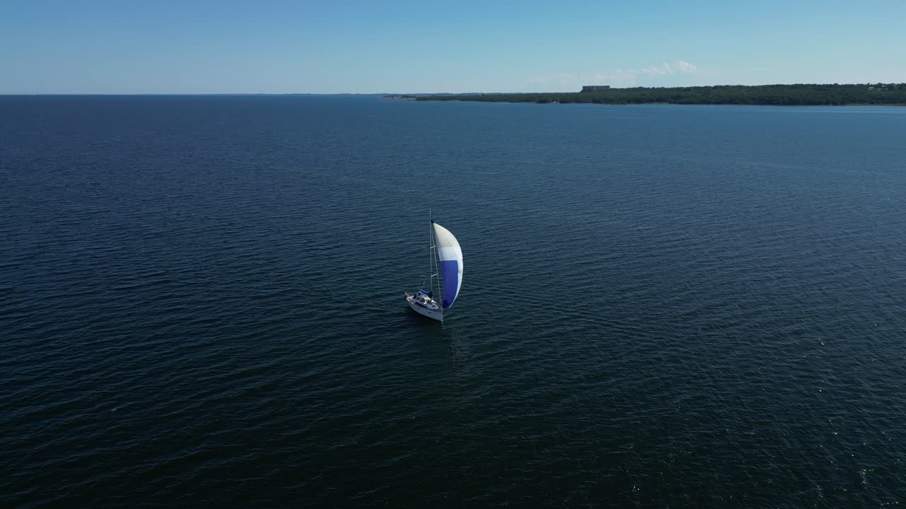 perspectiva aérea de un velero navegando con su vela vibrante, deslizándose en las aguas oscuras del mar báltico