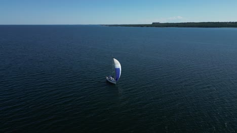 Perspectiva-Aérea-De-Un-Velero-Navegando-Con-Su-Vela-Vibrante,-Deslizándose-Sobre-Las-Oscuras-Aguas-Del-Mar-Báltico