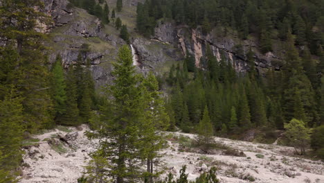 vista panorámica de una cascada en las montañas dolomitas rodeada de un exuberante bosque de pinos