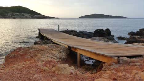 serene sunset at a wooden pier on a rocky coast