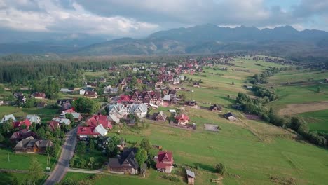 aerial of small resort in polish tatra mountains. drone rotates slightly and flies away from the buildings, revealing the majestic mountain range.