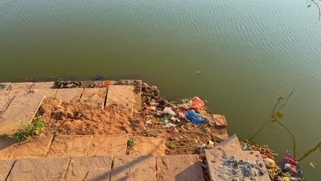 trash in bank of river or pond, people litter water bodies in india
