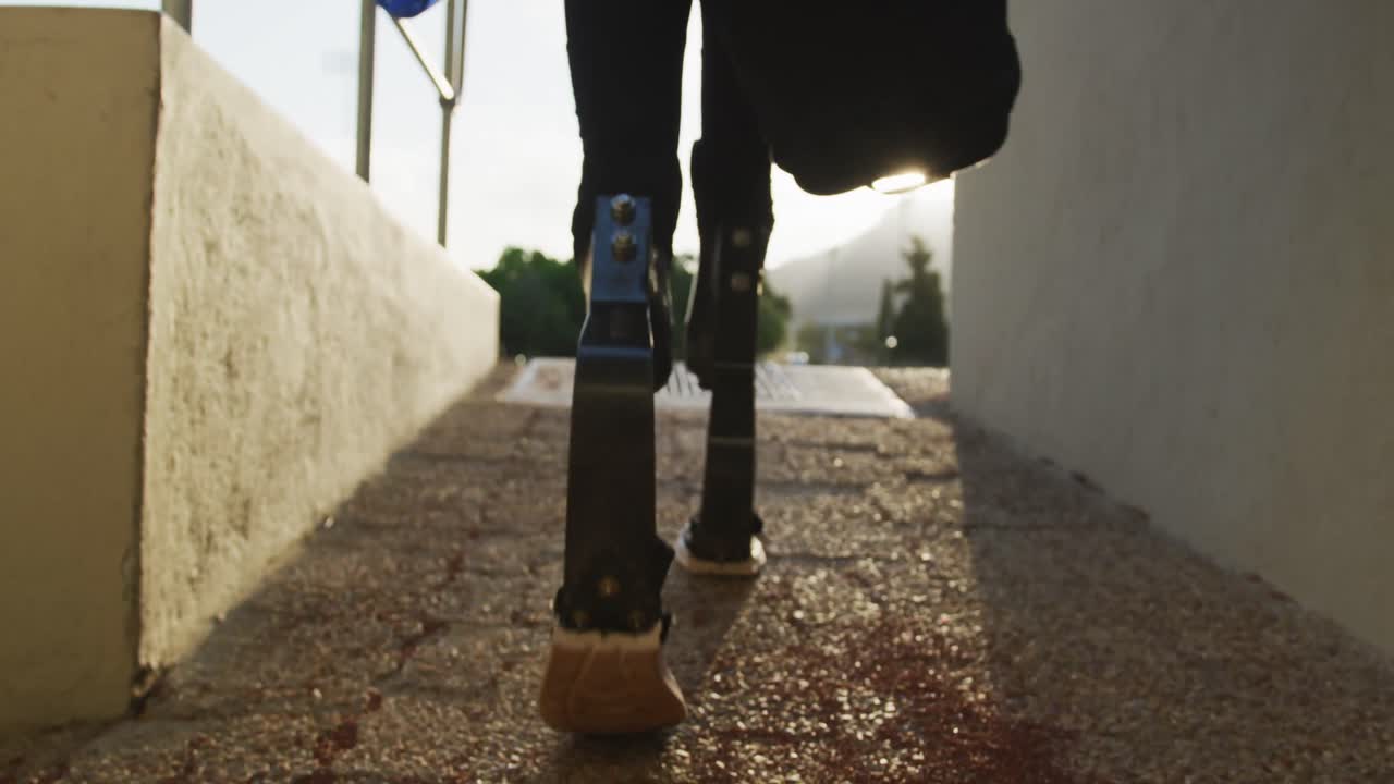 hombre de raza mixta discapacitado con piernas protésicas caminando hacia el estadio deportivo