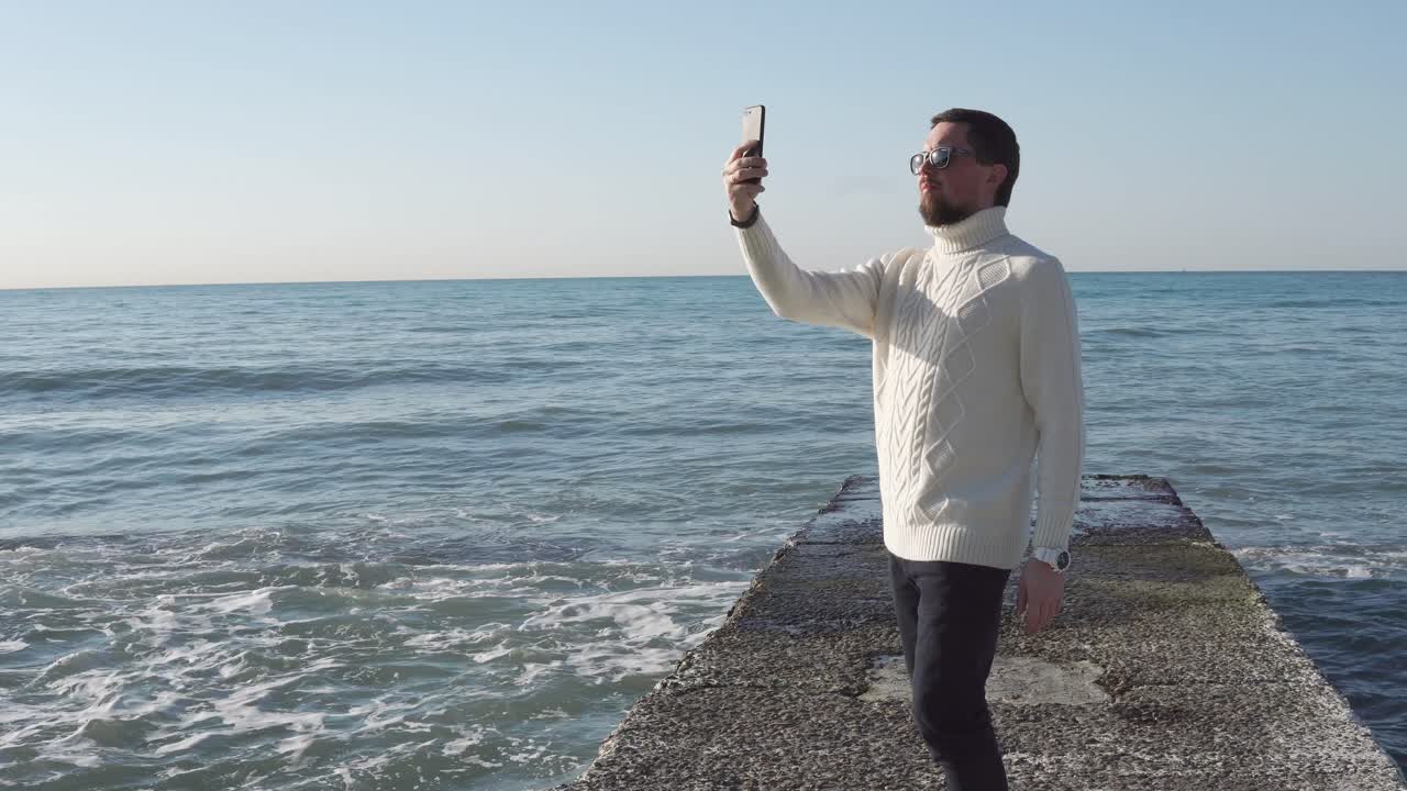 hombre tomando una selfie en un muelle de la playa