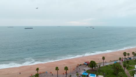 Dolly-in-aerial-view-of-a-flight-between-buildings-and-El-Sol-beach-in-ViÃ±a-del-Mar,-Chile