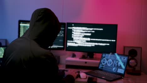 hacker in felpa con cappuccio che lavora su un laptop all'interno della sua stanza