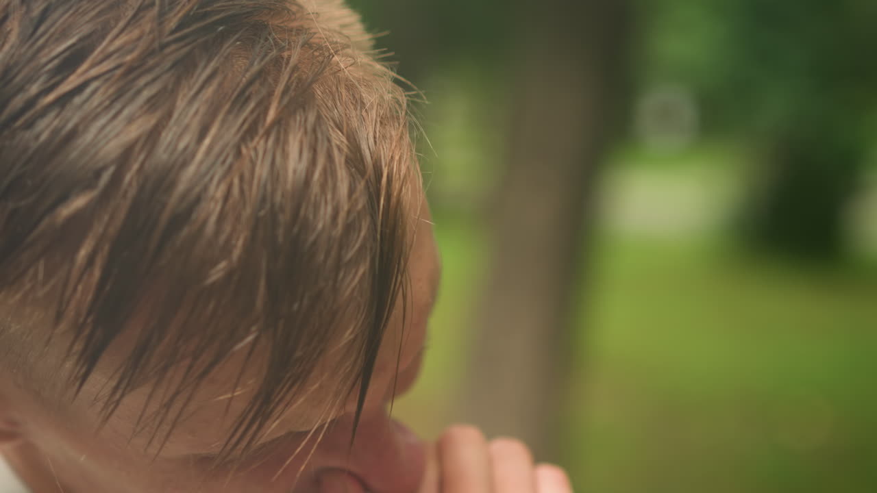 공원에서 코를 닦는 백인 남성, 젖은 머리카락과 축축한 후드티를 입고 눈물이 글썽한 얼굴을 클로즈업, 지친 달리기 선수에서 슬픔에 잠긴 학생, 사색에 잠긴 정원사로 바뀌는 순간, 날것의 감정, 얕은 심도, 초록색 보케