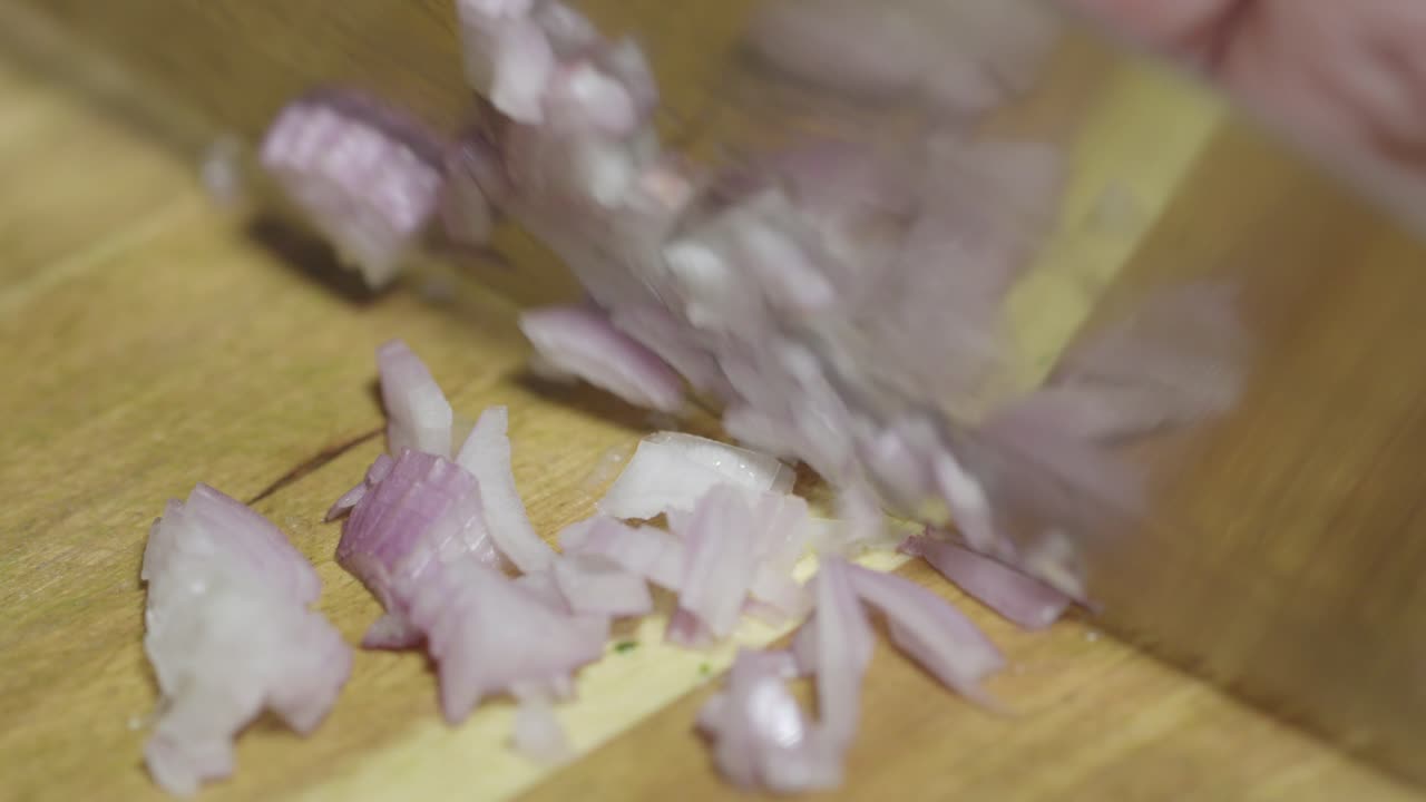 Close-up of chopping shallots with a knife on a cutting board