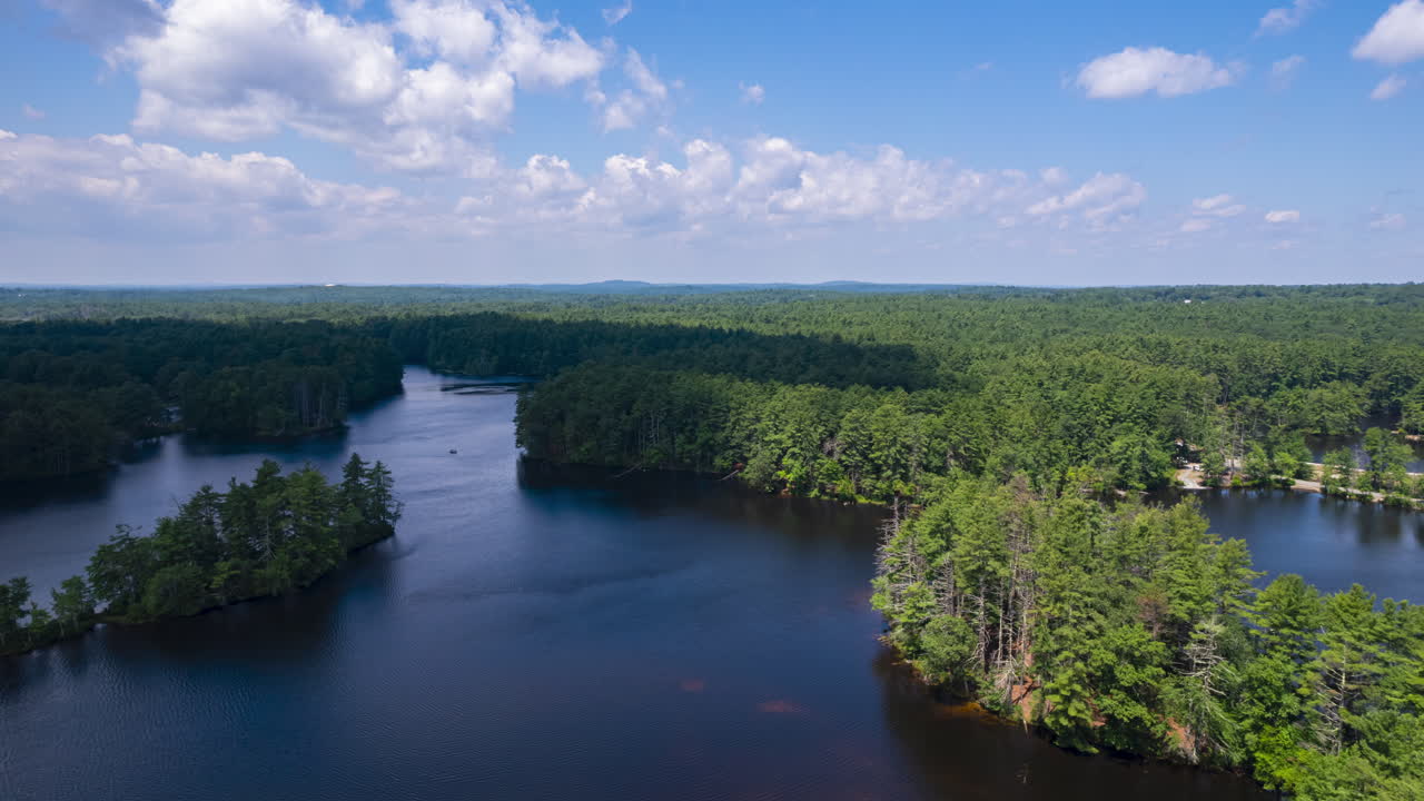 Aerial time lapse of American forest landscape with natural lake and cloud shadows on water surface. Hyperlapse shot. Harold Parker forest in MA, USA