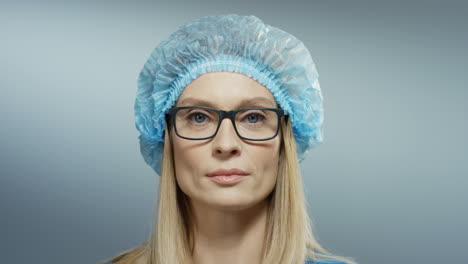 Retrato-De-La-Hermosa-Mujer-Médica-Con-Gafas,-Sombrero-Azul-Sonriendo-Alegremente-A-La-Cámara