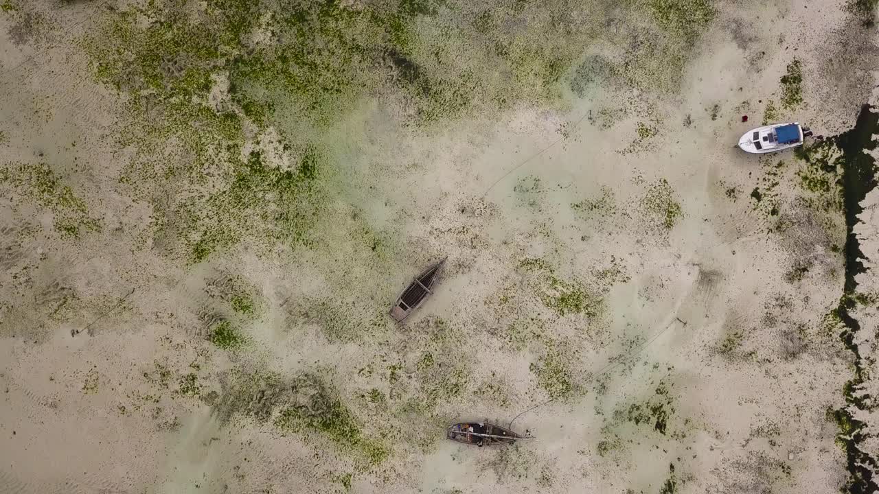 Aerial birdseye flying over boats stranded on sand during low tide