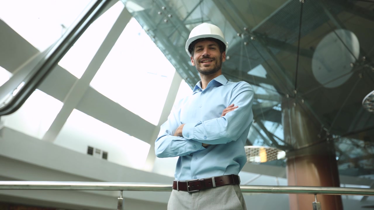 Ingeniero seguro con sombrero de pie en un edificio moderno