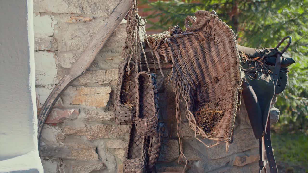 Scarpe tradizionali intrecciate e cesto appesi a un muro di pietra