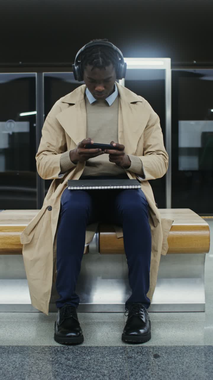 Man with Headphones Using Cellphone at Subway Station