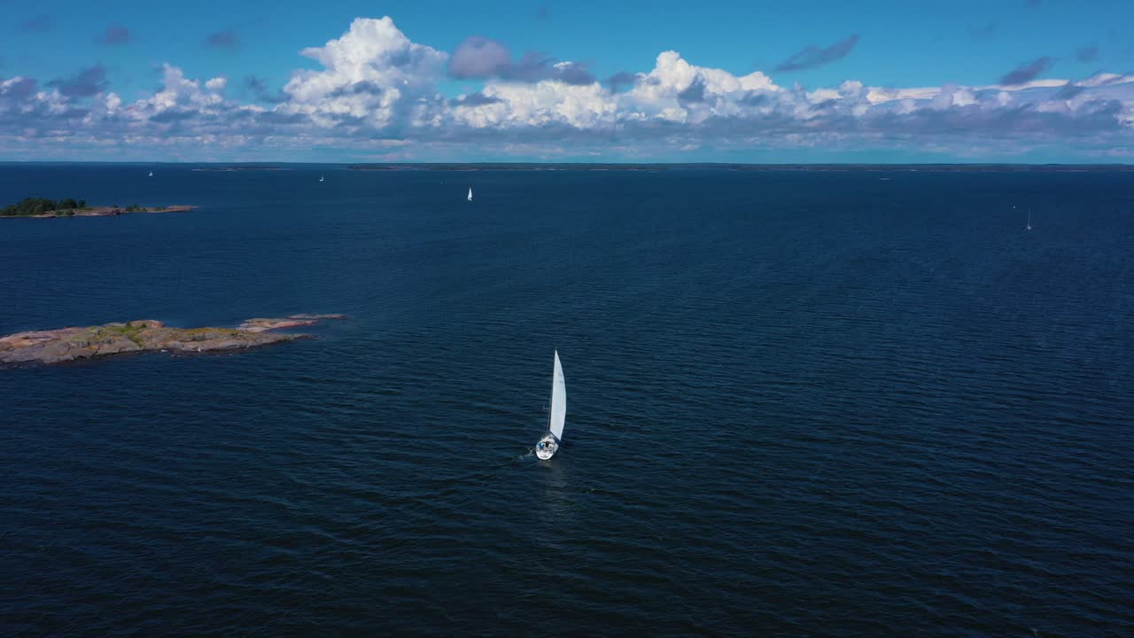 Aerial view overlook a white sailboat on the high seas, calm breeze at the Baltic sea, warm, sunny, summer day, in Uusimaa, Finland - tracking, drone shot